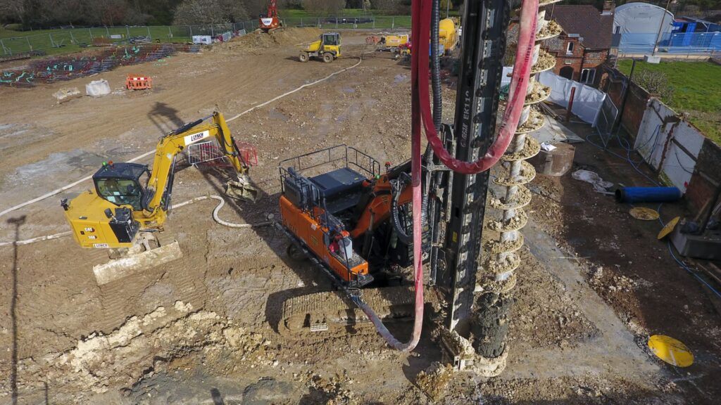 A large piling machine in use at the Rayners Penn site with other construction vehicles in the background